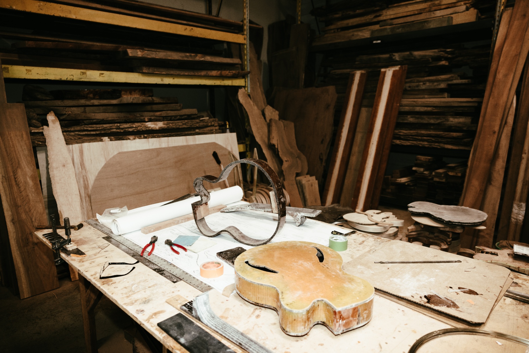 Cardboard body shell resting on the workbench beside the rim and plans