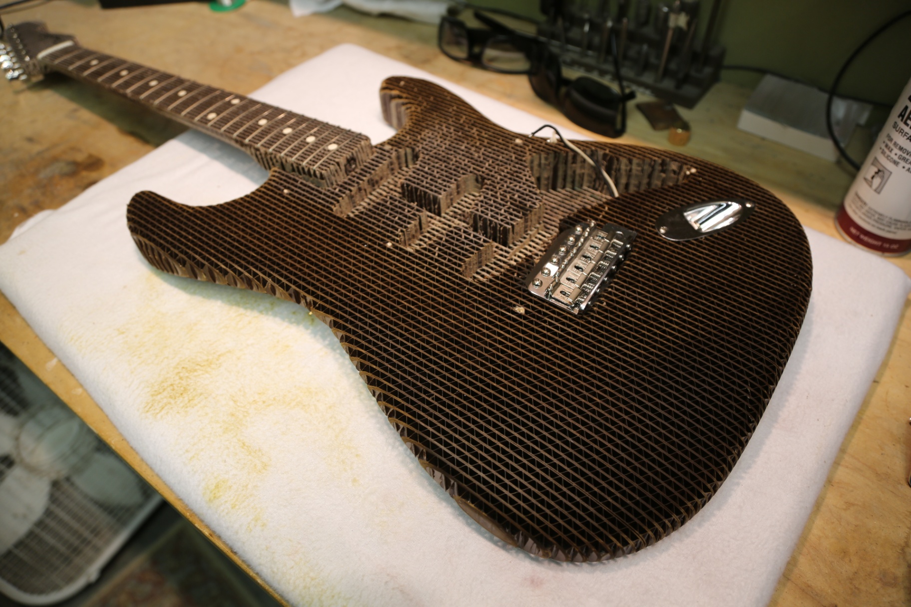 The unfinished cardboard Stratocaster body and neck laid out on the bench
