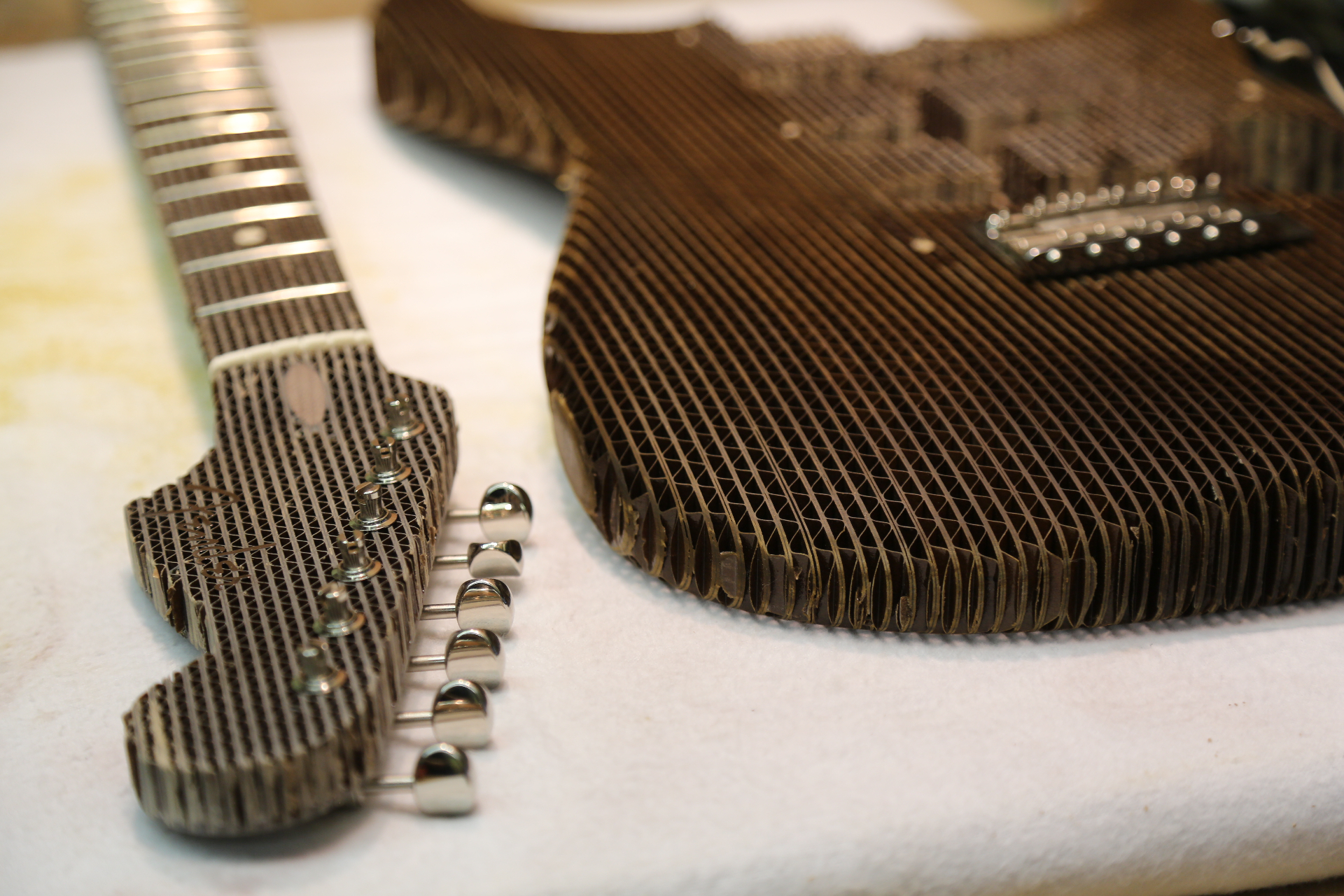 Cardboard Stratocaster neck and body components arranged before assembly