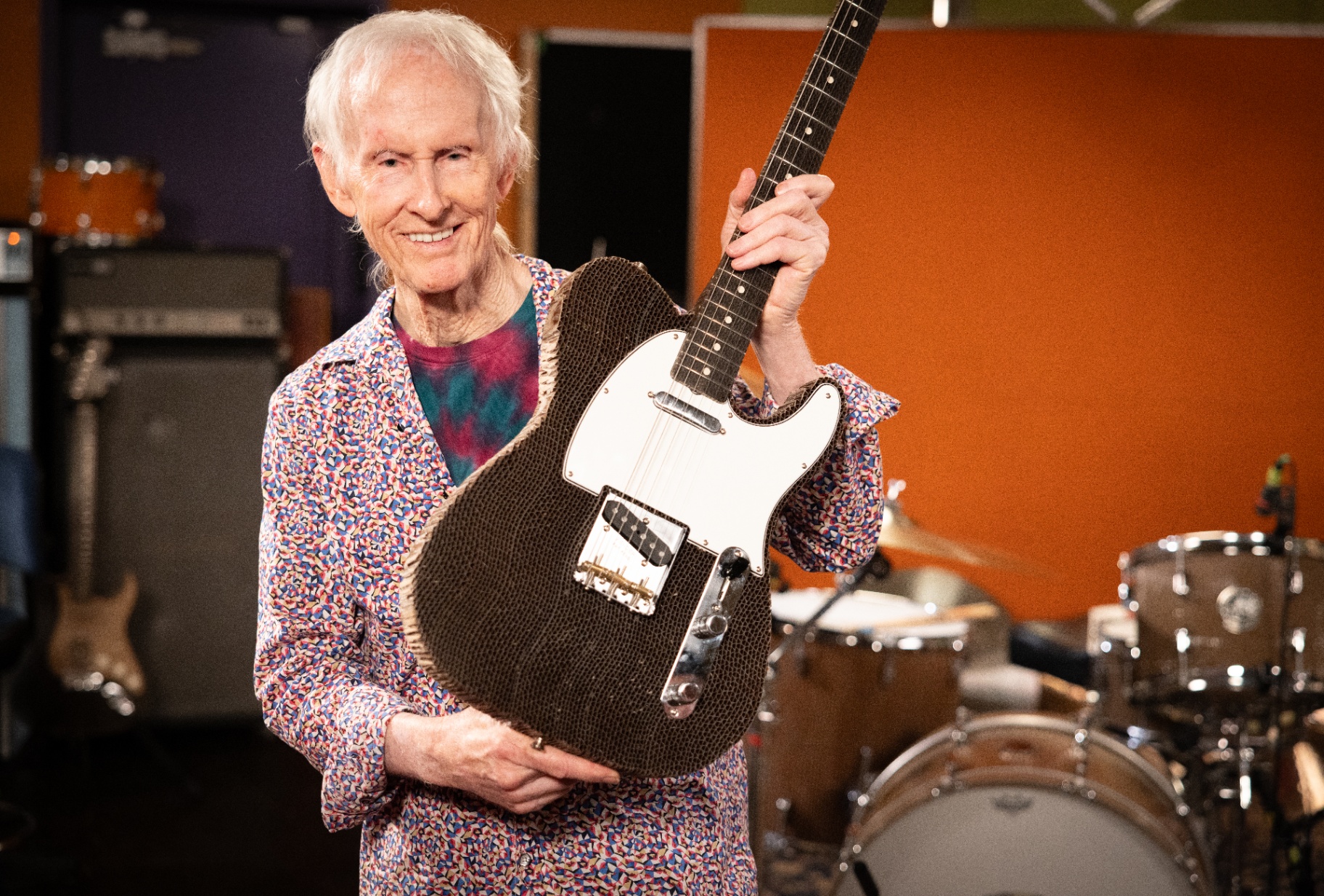 Robby Krieger smiling as he holds the finished cardboard Telecaster in the studio